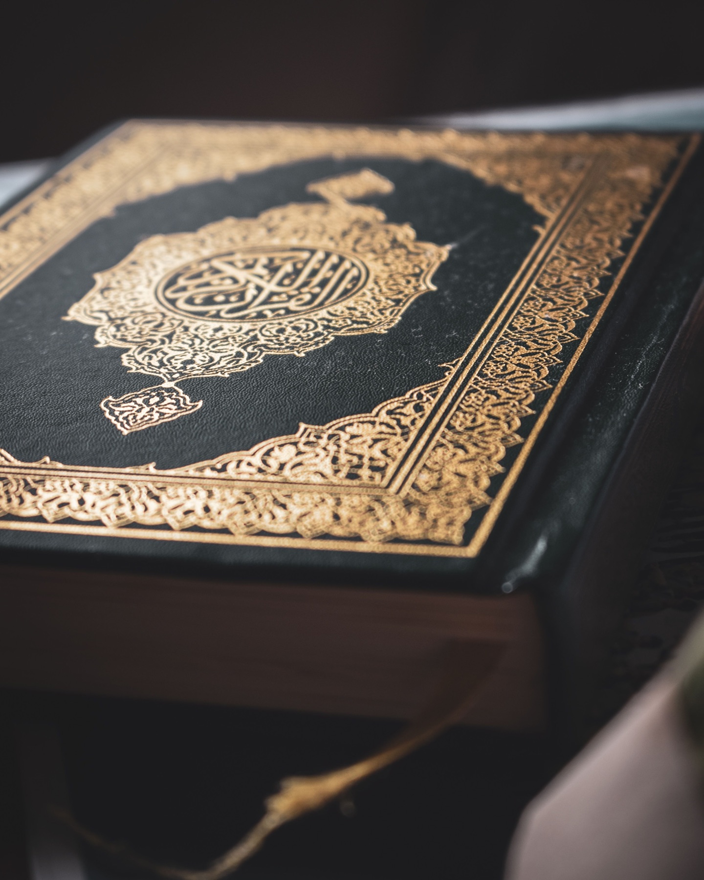 An ornate gold-embossed Qur'an resting on a wooden stand